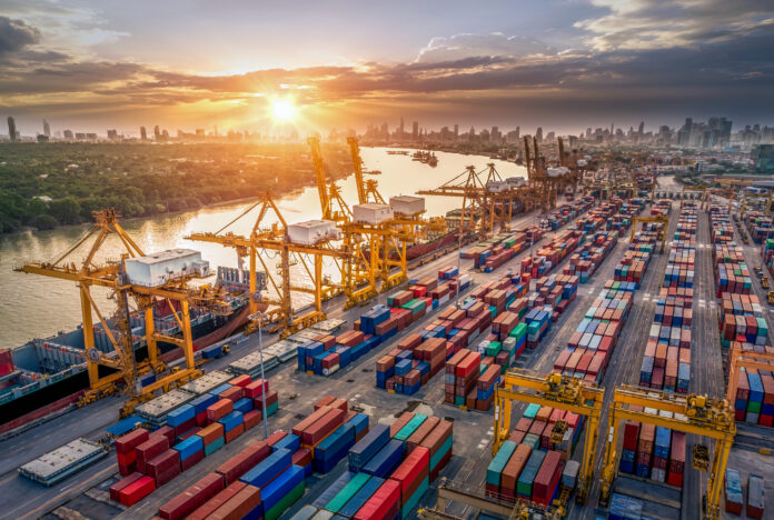 Logistics and transportation of Container Cargo ship and Cargo plane with working crane bridge in shipyard at sunrise, logistic import export and transport industry background